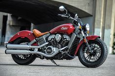 a red motorcycle parked in front of a bridge