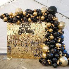 black and gold balloon arch with happy birthday sign