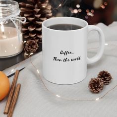 a white coffee mug sitting on top of a table next to an orange and some cinnamons