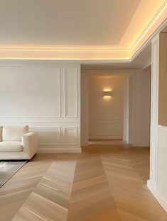 an empty living room with white furniture and wood flooring, lighting up the walls