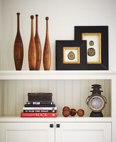 a white book shelf filled with books and vases on top of eachother