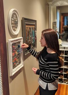 a woman is looking at some art on the wall and touching it with her hand