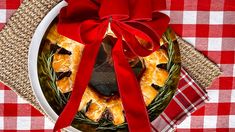 a red ribbon is tied around the top of a pie on a plate with a plaid tablecloth