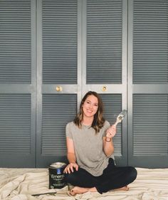 a woman sitting on a bed holding a paintbrush