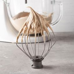 a whisk in a metal wire cage on top of a counter next to a mixer