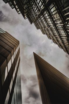 looking up at two tall buildings from the ground, with clouds in the sky behind them