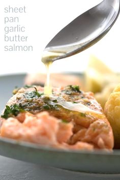 a spoon drizzling sauce over salmon on a plate