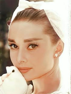 a woman wearing a white headband with her hand on her chin and looking at the camera