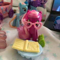 there are many toys on the table and one has a pink pony with glasses in front of it