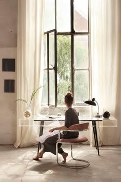 a woman sitting at a desk in front of a window