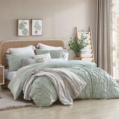 a bed in a bedroom with a green comforter and pillows on the floor next to a window