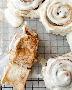 cinnamon rolls with icing sitting on top of a cooling rack