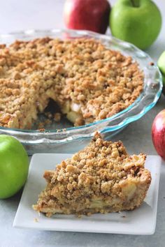 an apple crumb pie on a plate next to some apples