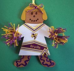 a paper cut out of a cheerleader with purple and yellow pom - poms