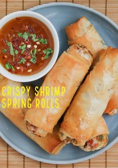 crispy shrimp spring rolls on a blue plate with dipping sauce and garnish