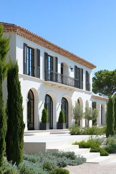 a large white house surrounded by trees and bushes