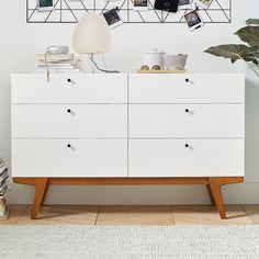 a white dresser sitting next to a wall with pictures hanging on it's sides