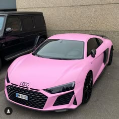 a pink car parked next to a black suv