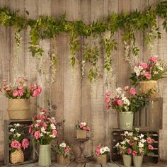 three vases filled with flowers sitting on top of a wooden table next to a wall