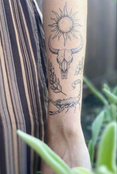 a person with a sun tattoo on their arm next to some plants and flowers in the background