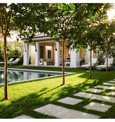 a house that is next to a pool with grass on the ground and trees in front of it