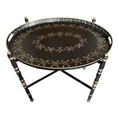 a black and gold tray with floral designs on the top, sitting on a stand