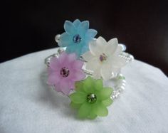 three different colored flowers are on top of a white cloth covered pillow with pearls and beads