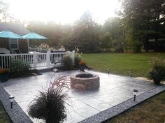 a patio with a fire pit surrounded by landscaping