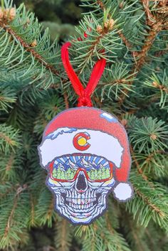 a christmas ornament with a skull wearing a santa hat on top of a pine tree