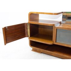 a wooden cabinet with glass doors and shelves on the bottom shelf is open to reveal a piece of furniture