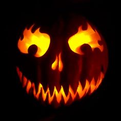 a carved pumpkin with glowing eyes in the dark