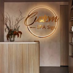 a spa sign is lit up on the wall next to a vase with flowers in it