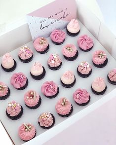 a box filled with lots of pink cupcakes