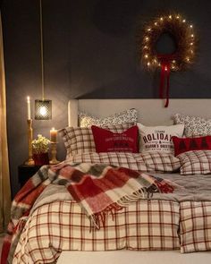 a bed with red and white plaid comforter next to a wreath on the wall