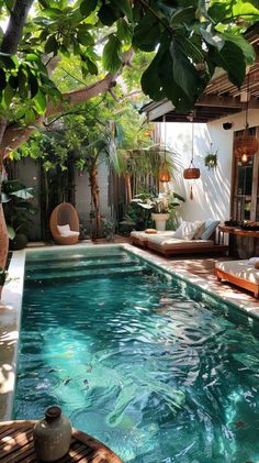 an outdoor swimming pool surrounded by greenery and hanging lights, with wicker chairs around it