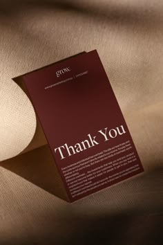 a folded thank card with the words thank you on it in white and red ink