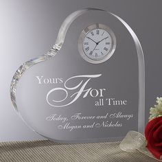 a heart shaped glass clock with the words yours for all time and a red rose