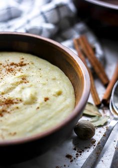 a wooden bowl filled with mashed potatoes on top of a table next to spoons