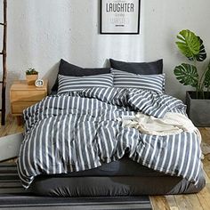 a bed with black and white striped comforter in a room next to a plant