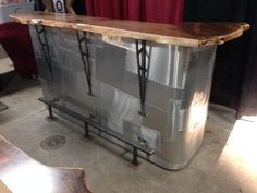 a large metal and wood bar on display in a room with red curtained windows