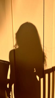 the shadow of a person's head on a wall next to a wooden chair