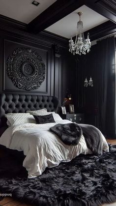 a black and white bedroom with a chandelier hanging from the ceiling, an upholstered headboard