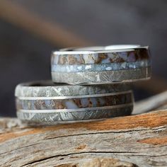 two wedding bands made out of silver and white marble are sitting on a piece of wood