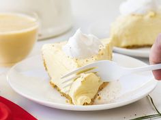 a person holding a fork over a piece of pie on a plate with whipped cream