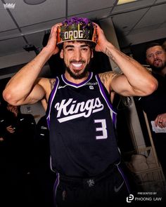 a man with a crown on top of his head in a basketball uniform and smiling