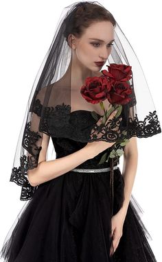 a woman in a black dress with a veil and red roses on her shoulder,