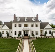 a large white house sitting on top of a lush green field