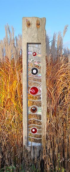 a tall wooden sign sitting in the middle of a field next to some dry grass