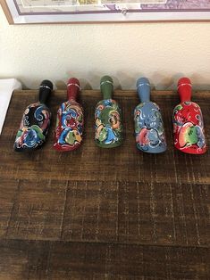 five different colored vases sitting on top of a wooden table next to a wall