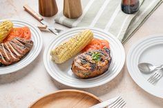 three plates with grilled meat, corn on the cob and tomatoes next to each other